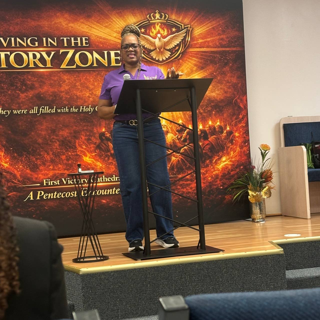 A minister speaking from a lectern in front of a sanctuary backdrop