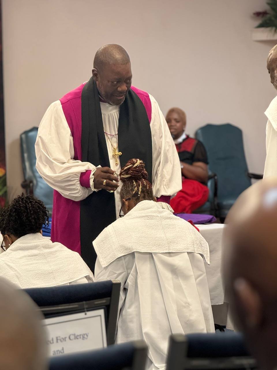A minister praying over a kneeling clergy member