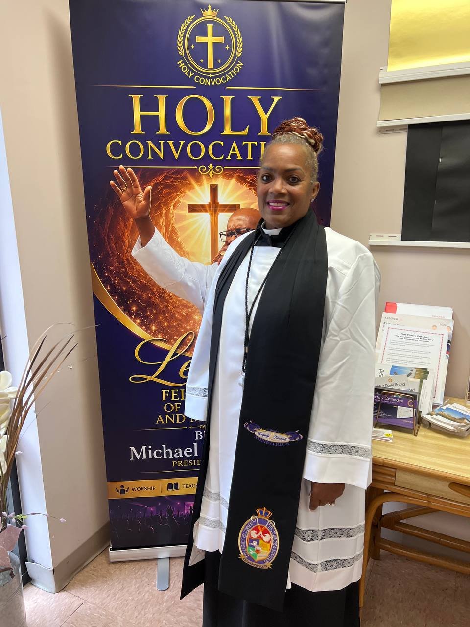 A minister standing beside a Holy Convocation banner
